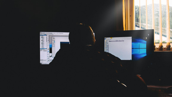 A worker sites in front of two computer screens