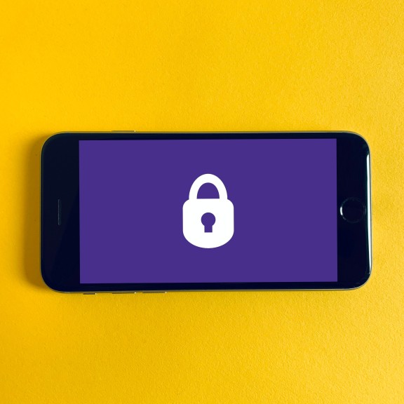 Yellow background, smart phone with purple screen and a white lock.