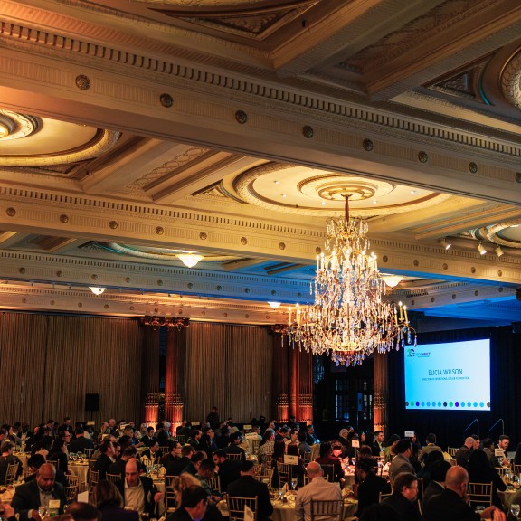 Crowd of event attendees in a historic ballroom sitting at tables
