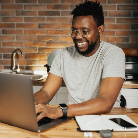 A person smiling while working on a laptop