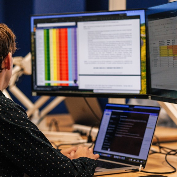 Man sitting at desk looking at 2 monitors