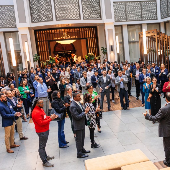 A man speaking to a crown in an atrium