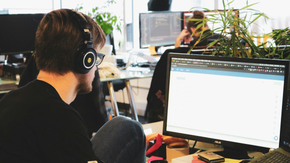 A person wearing headphones and working at a computer station in an office setting