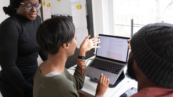 Three people working together at a laptop