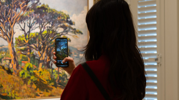 Women holding her phone taking a picture of a museum art piece