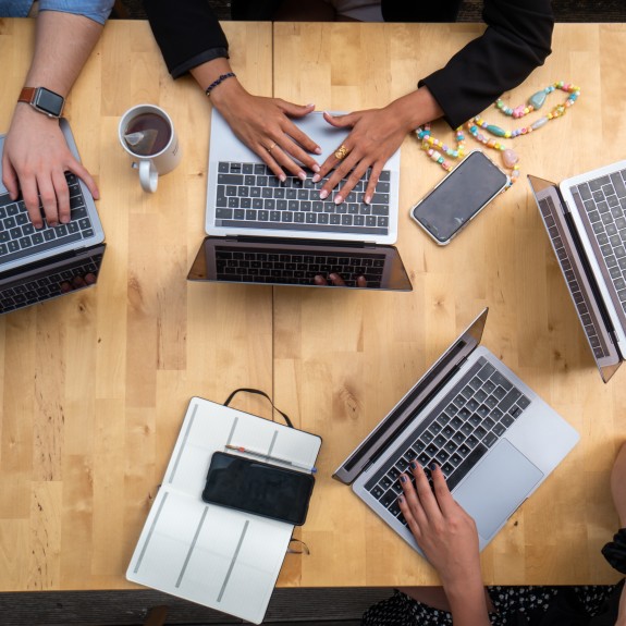 top view of 4 laptops and people working on them
