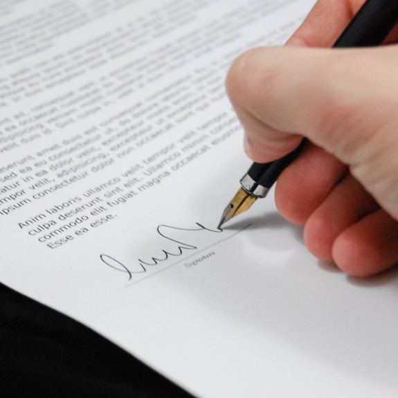 Hand holding pen signing a contract