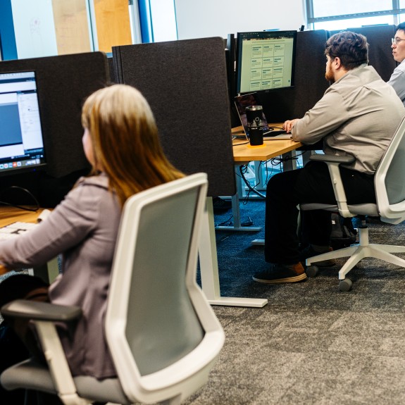 Four adults sitting at computer desks