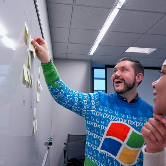 Two people collaborating at a white board in an office setting 