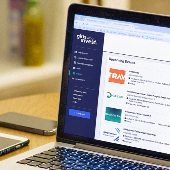 A young woman looking at a laptop with the Girls Who Invest portal events screen
