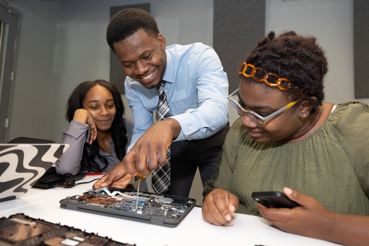 A man showing two women the hardware of a computer