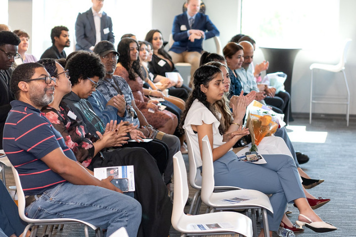 A crowd of people sitting in chairs clapping