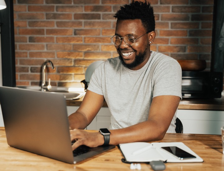 A person smiling while working on a laptop