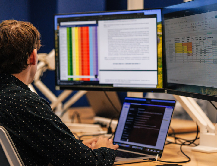 Man sitting at desk looking at 2 monitors