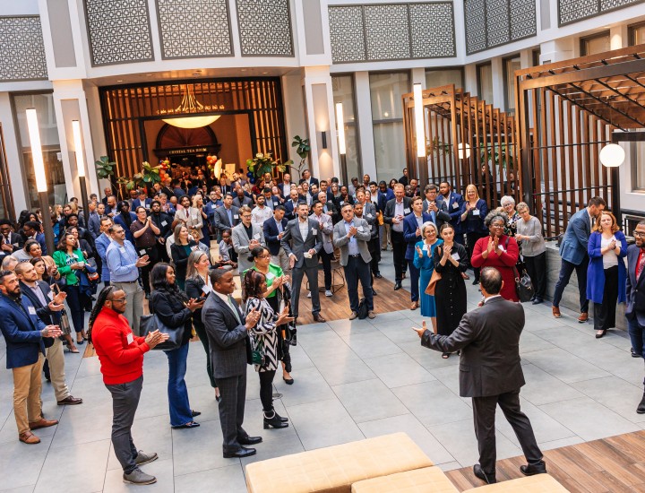 A man speaking to a crown in an atrium